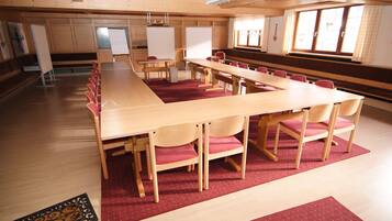Una sala conferenze con un lungo tavolo, diverse sedie e una moquette rossa.
