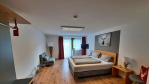 Un dormitorio moderno con una cama grande, un sofá, un escritorio y un televisor.