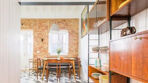 A dining area with a brick wall, wooden furniture, and a patterned floor. - Patio São Vicente Guest House (Lisbon)