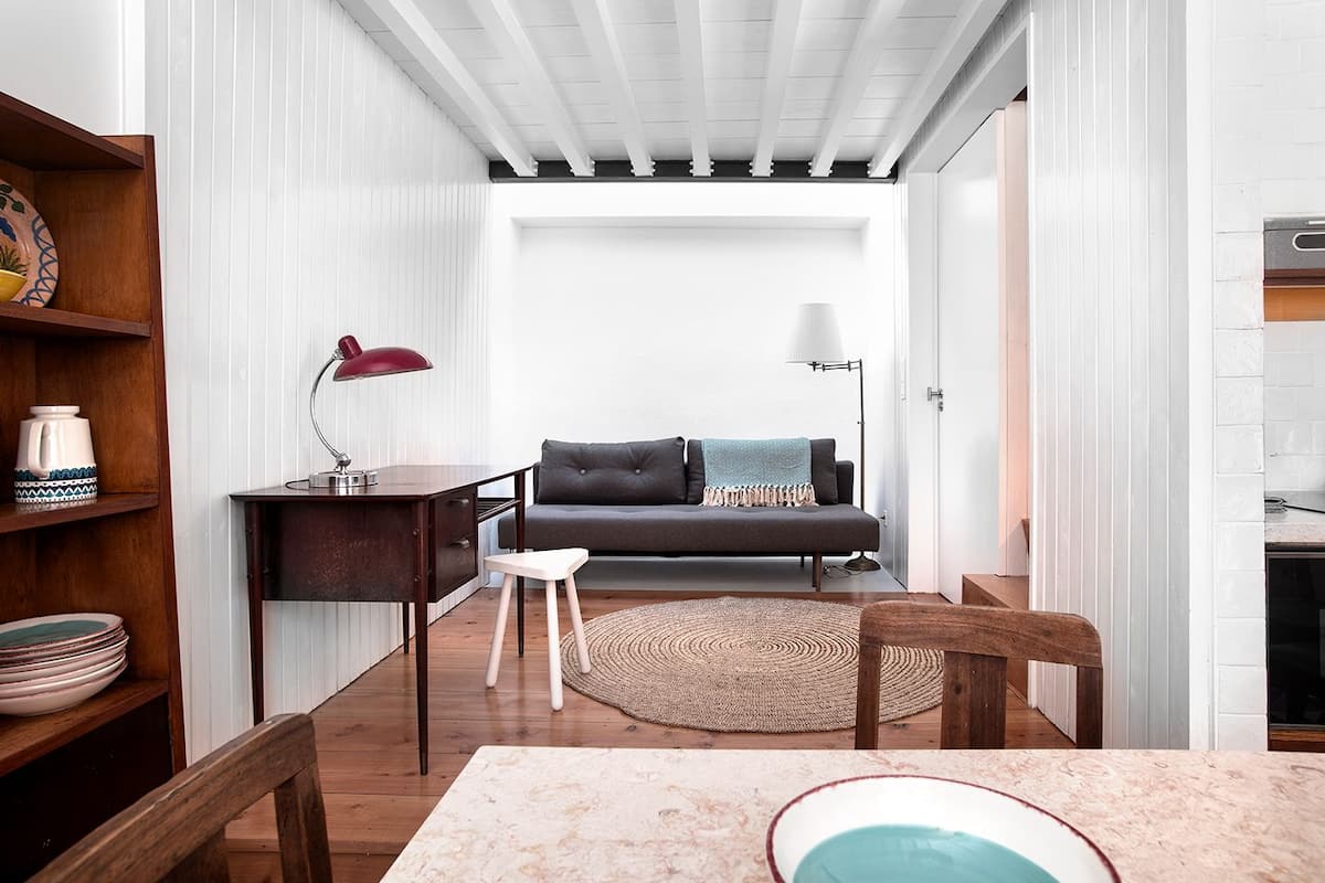 A compact living space with a sofa, a small table, a lamp, and a wooden chair.