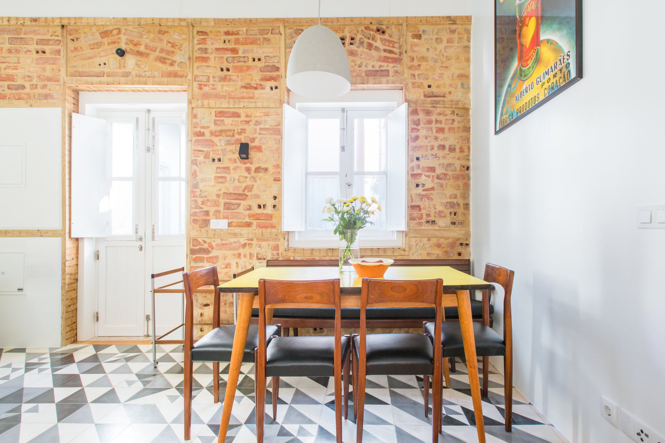 Un comedor con pared de ladrillo, puerta blanca y mesa con sillas.