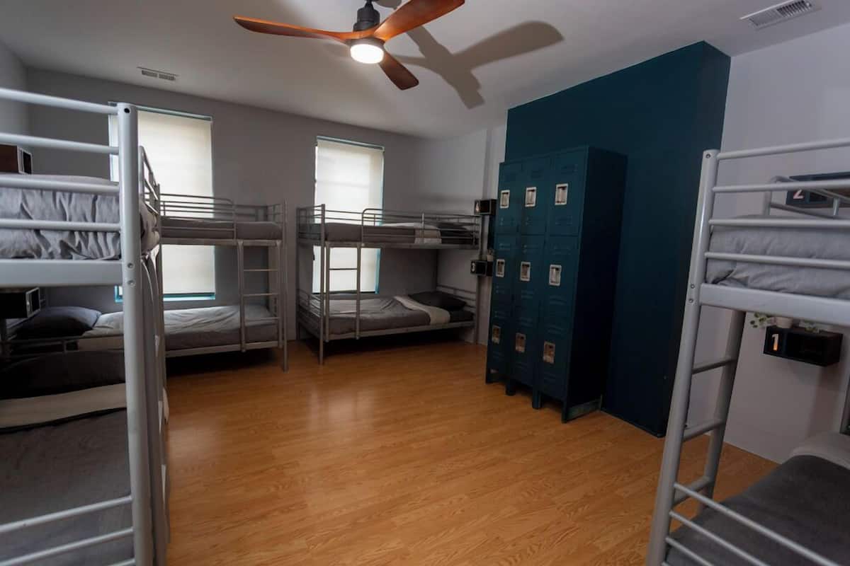 A dormitory room with bunk beds, a ceiling fan, and a set of lockers.