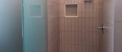 A modern shower with a glass door, a tiled wall, and a floor with hexagonal tiles.