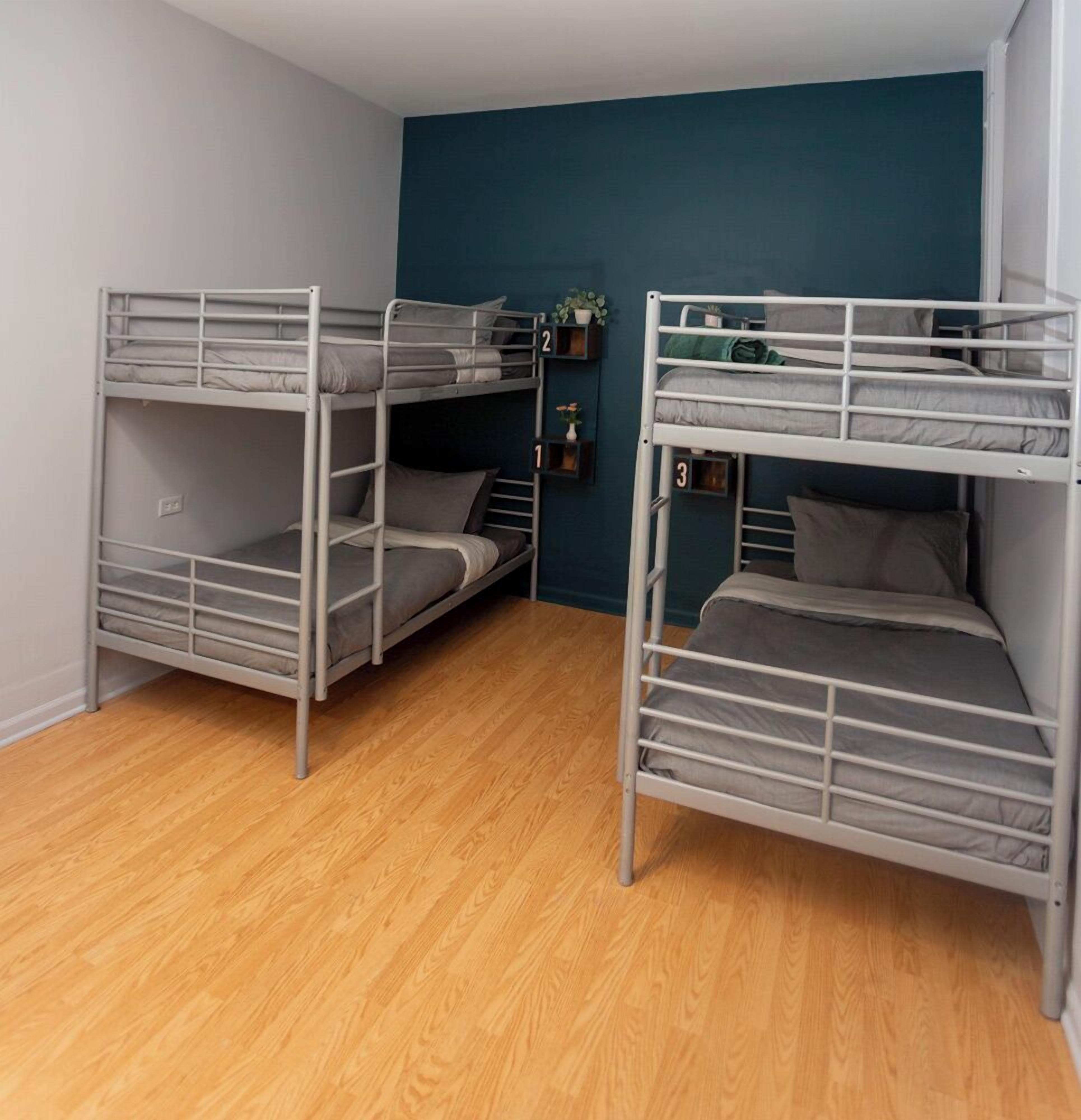 Een kamer met drie stapelbedden, houten vloeren en teal muren.