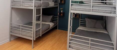 Een kamer met drie stapelbedden, houten vloeren en teal muren.