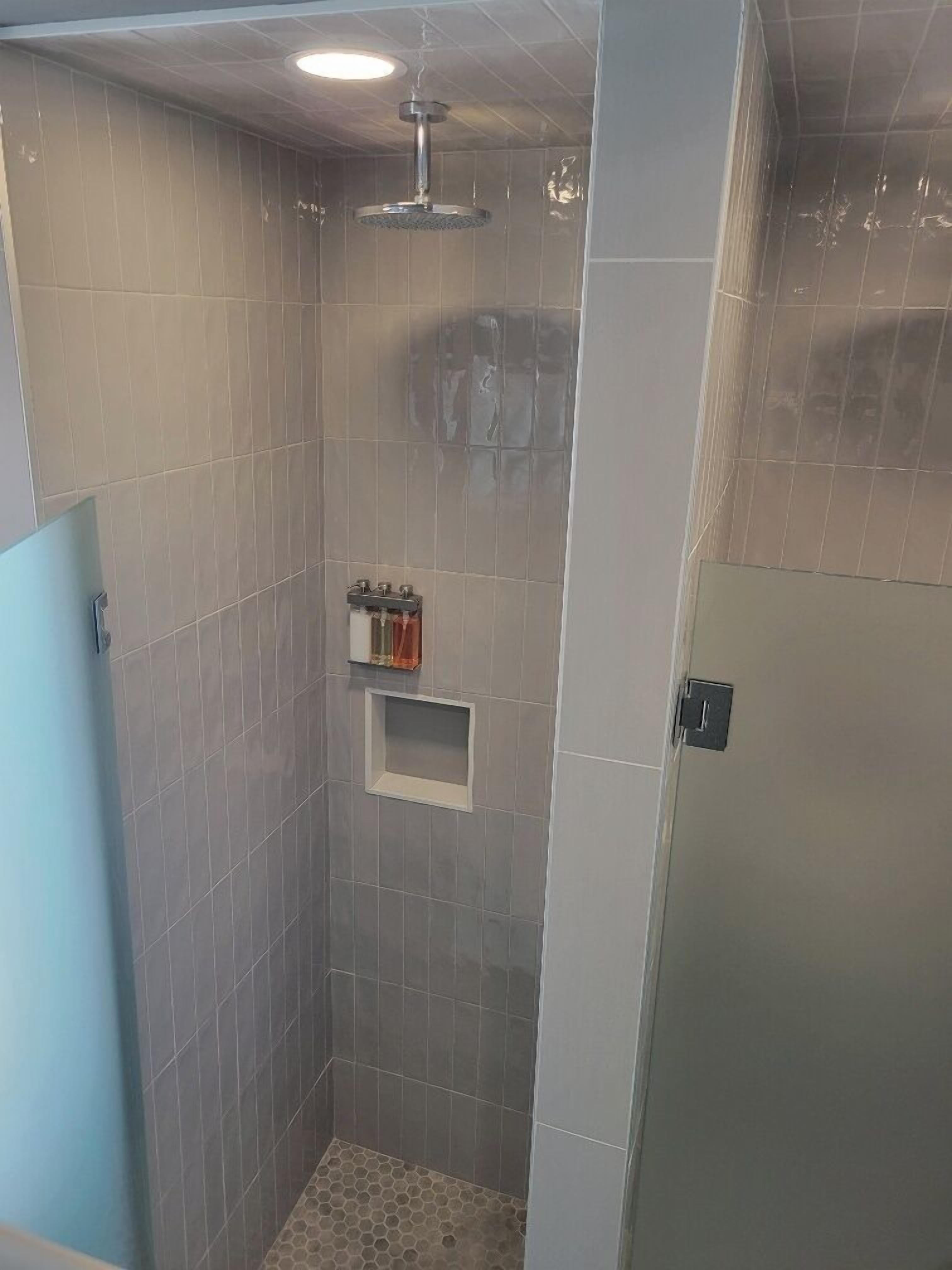Un espacio de ducha pequeño y cerrado, con paredes de azulejos e iluminación en el techo.