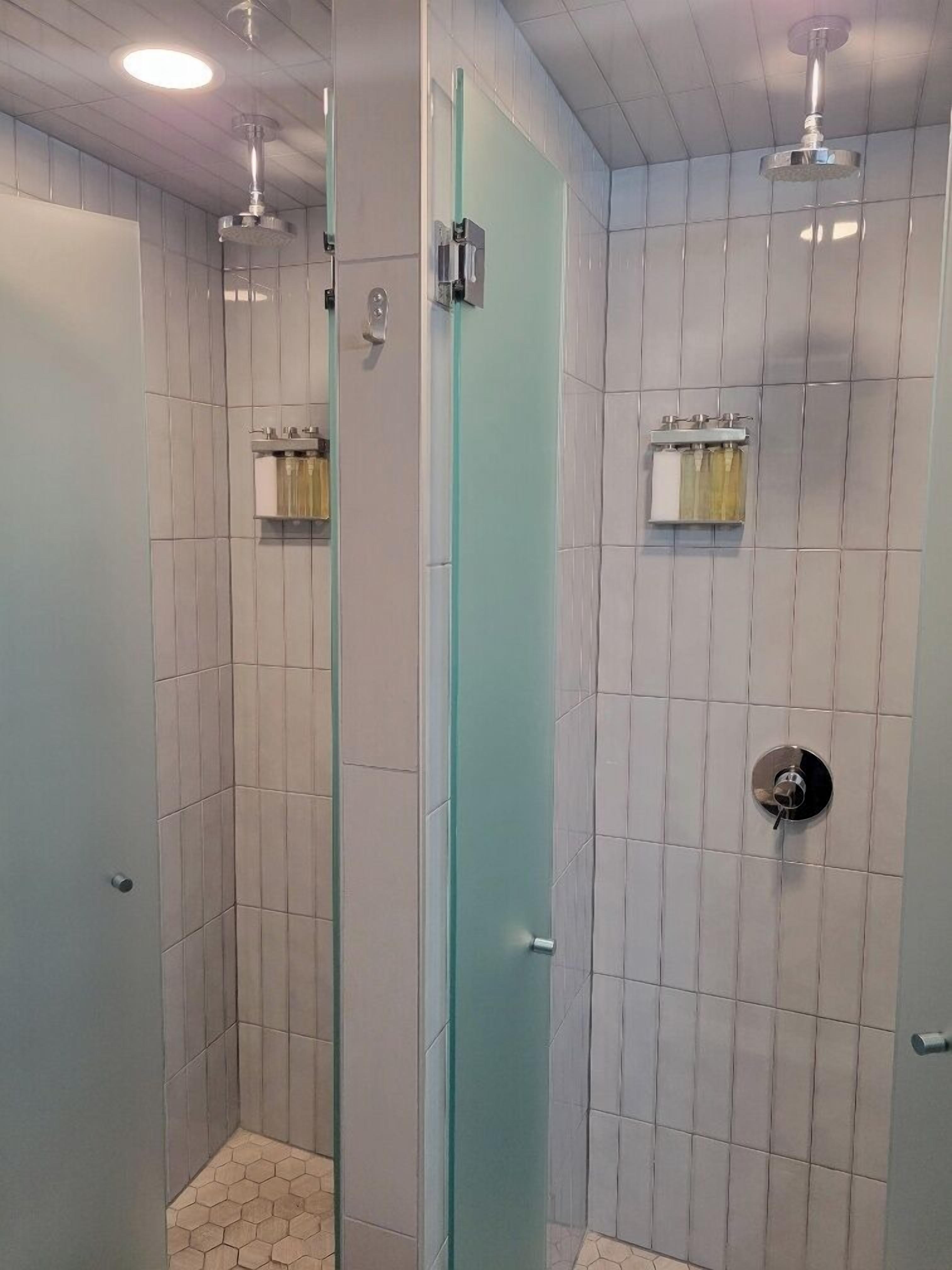 A modern bathroom with a glass partition, a shower with a handheld showerhead, and a toilet with a bidet attachment.