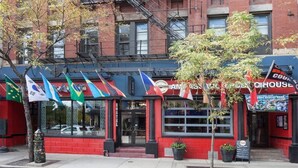 A red building with multiple flags, a sign reading "AMAZON HOUSE," and a storefront with a sign that says "COUNTRY HOUSE." - Chicago Parthenon Hostel (Chicago)