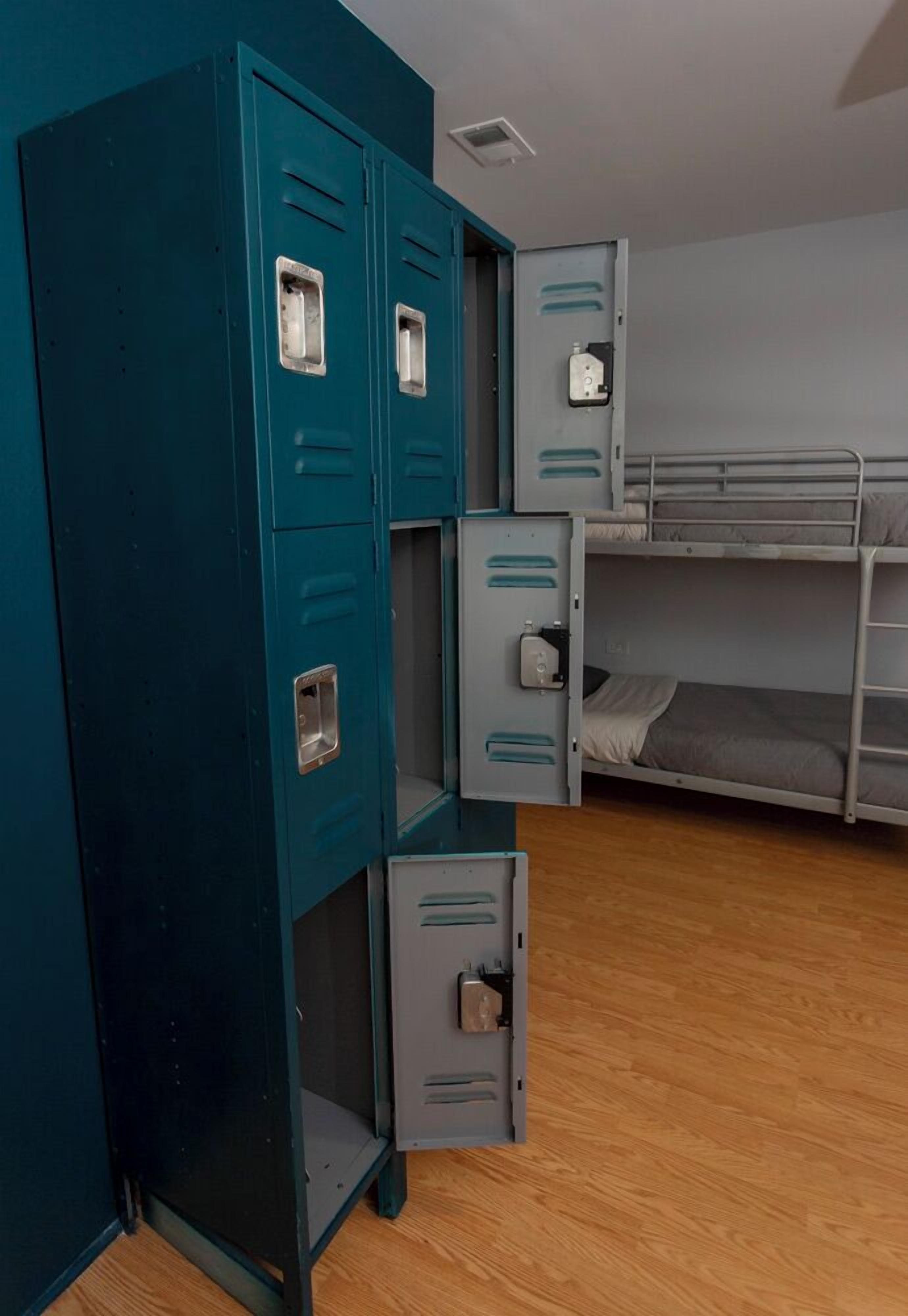 Een slaapkamer met stapelbedden, blauwgroene kasten en een houten vloer.