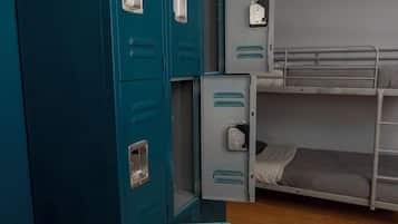 Een slaapkamer met stapelbedden, blauwgroene kasten en een houten vloer.