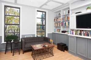 Una sala de estar moderna con un sofá gris, una mesa de centro y una estantería llena de libros.