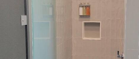 A walk-in shower with a glass door, tiled walls, and a ceiling showerhead.