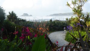 A pathway leading to a coastal view with lush greenery and flowering plants.