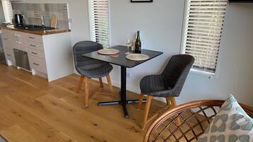 A modern kitchen with a dining area, featuring a table with chairs, a wine bottle, and a framed picture on the wall.