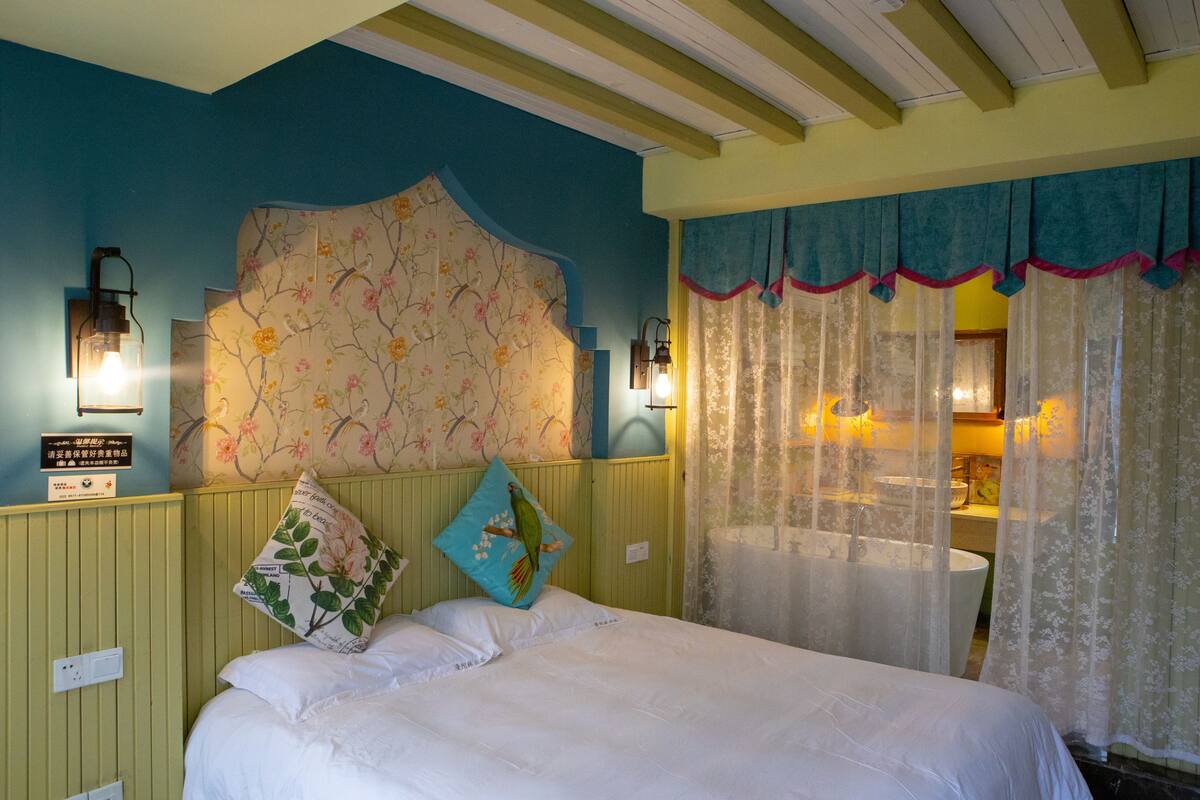 A bedroom with a bed, floral wallpaper, and a headboard.