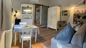 Een gezellige woonkamer met een bank, een eettafel met stoelen, een keuken met kastjes en een hanglamp.