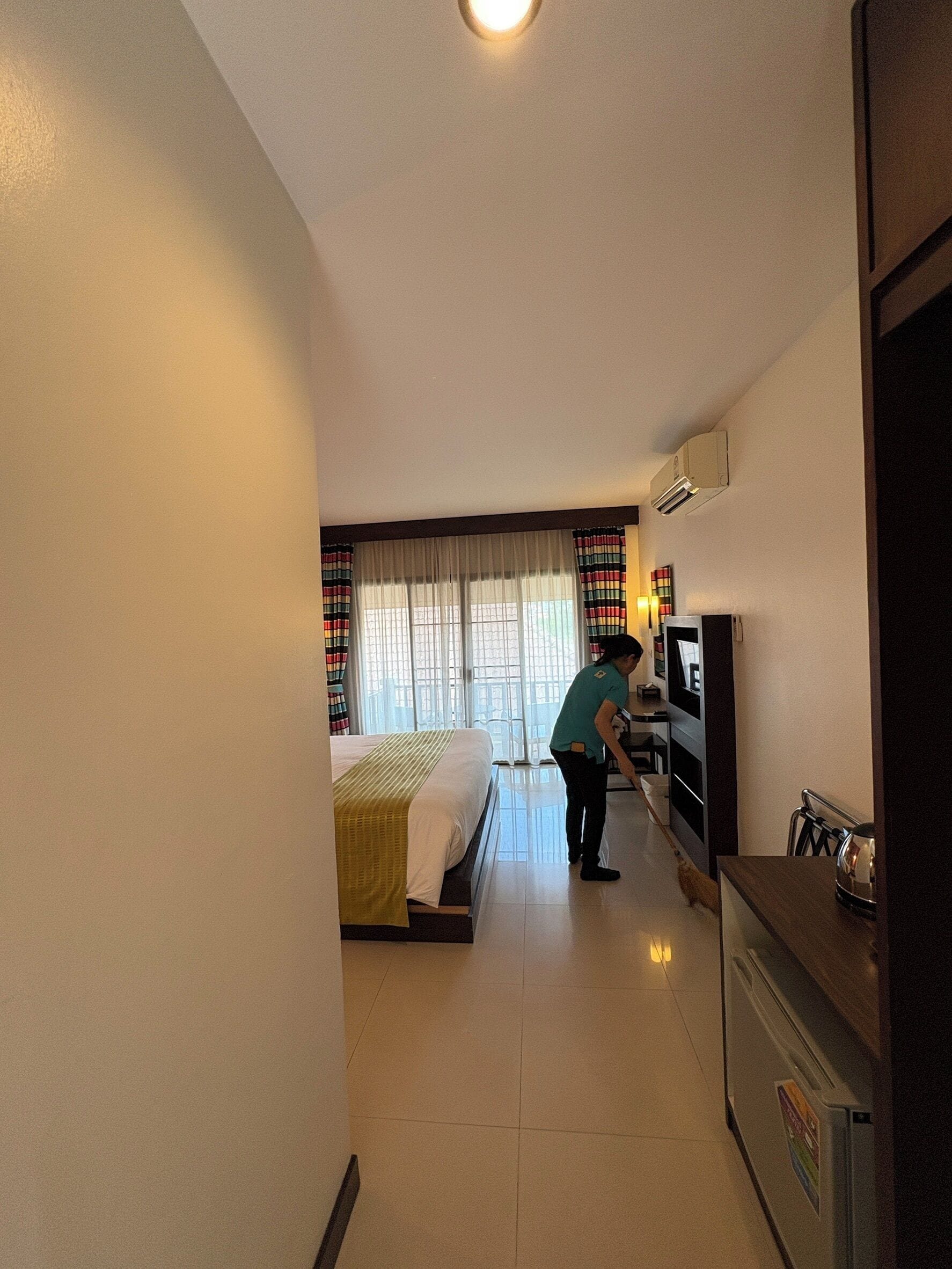 A hotel room with a bed, a TV, a desk, and a refrigerator.