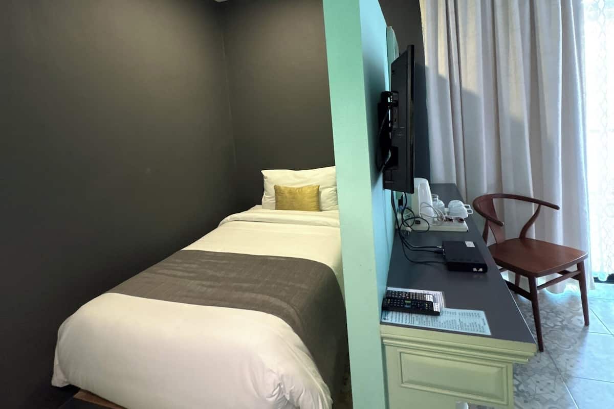 Une chambre dâhĂŽtel Ă©quipĂ©e dâun lit, dâun bureau, dâune chaise, dâune tĂ©lĂ©vision et dotĂ©e dâun sol Ă motifs.