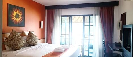 Une chambre d’hôtel avec un lit, un bureau, une télévision et une fenêtre avec des rideaux.