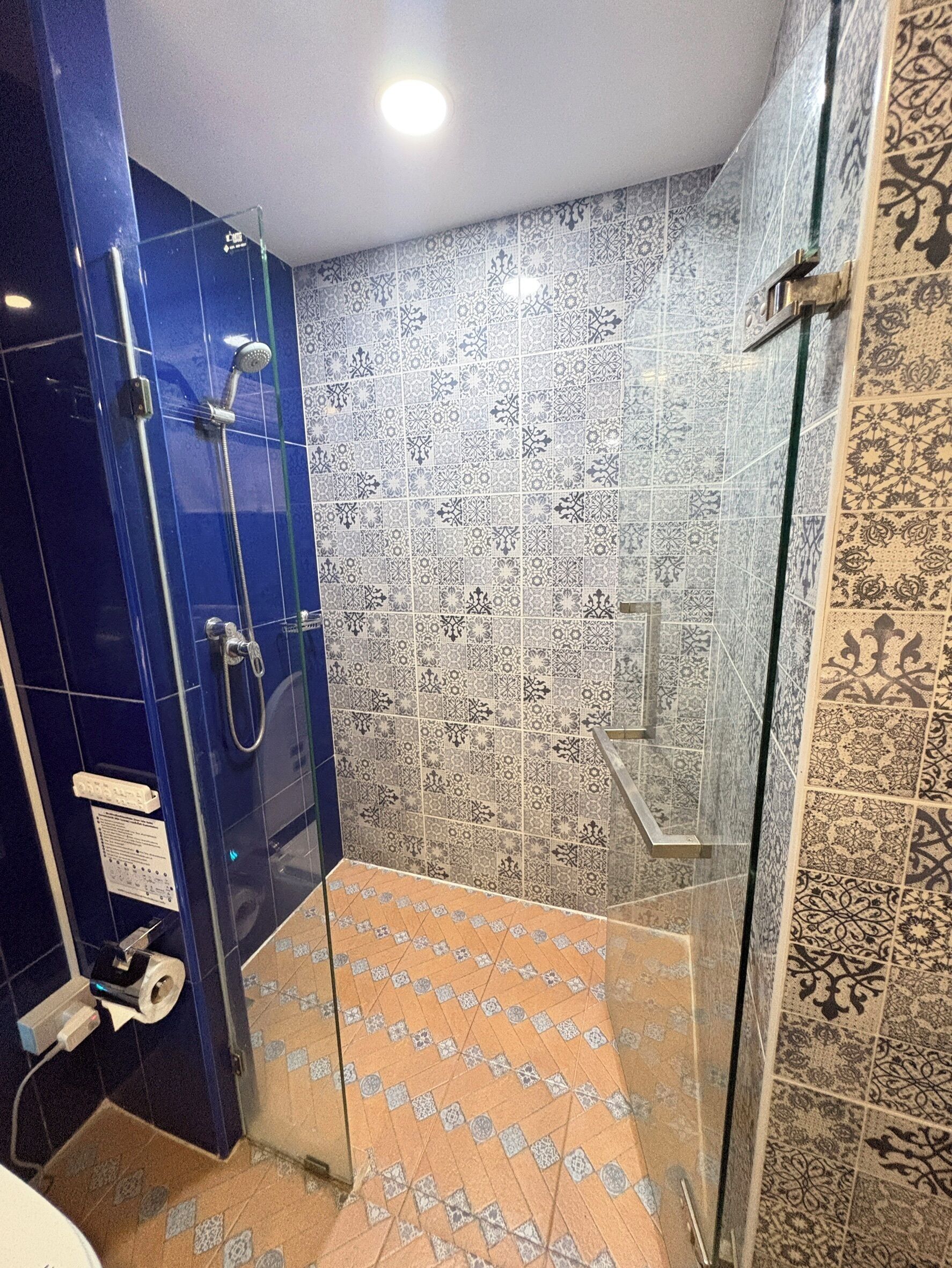 A bathroom with a glass shower enclosure, patterned tiles, and a blue accent wall.