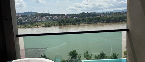 Un balcón con vistas a un río y un pueblo lejano.
