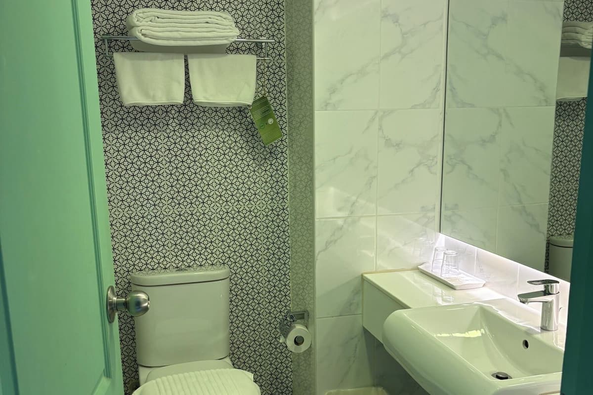 Une salle de bain Ă©quipĂ©e de toilettes, dâun lavabo et dâune poubelle.