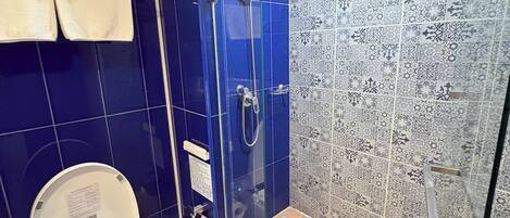 A bathroom with a toilet, a shower, and a patterned wall.