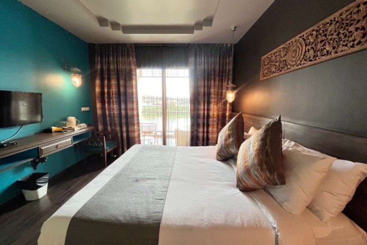 Une chambre d’hôtel avec un grand lit, un bureau avec un ordinateur, une télévision et une vue sur l’extérieur par la fenêtre.