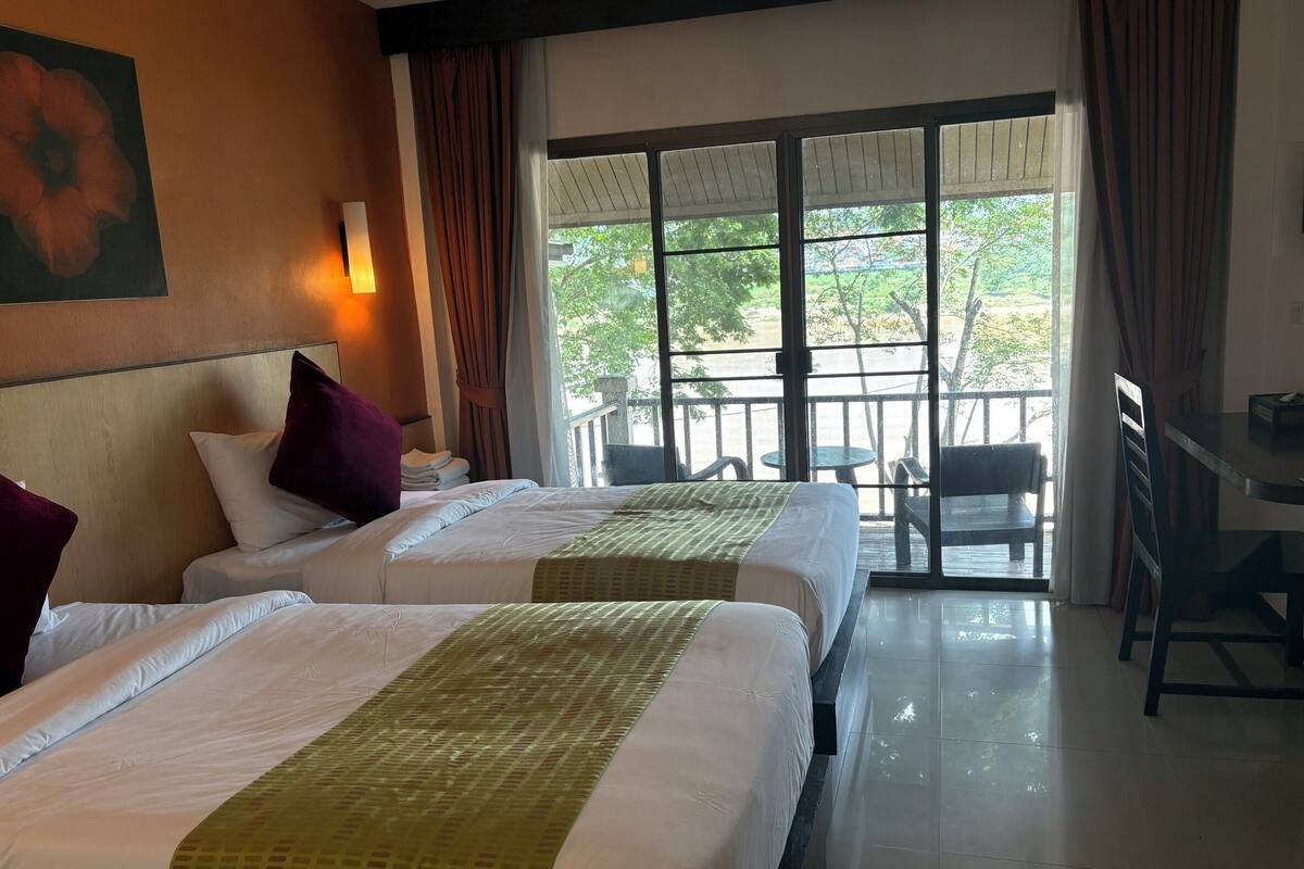 Una habitación de hotel con dos camas, un balcón con vistas y un comedor.