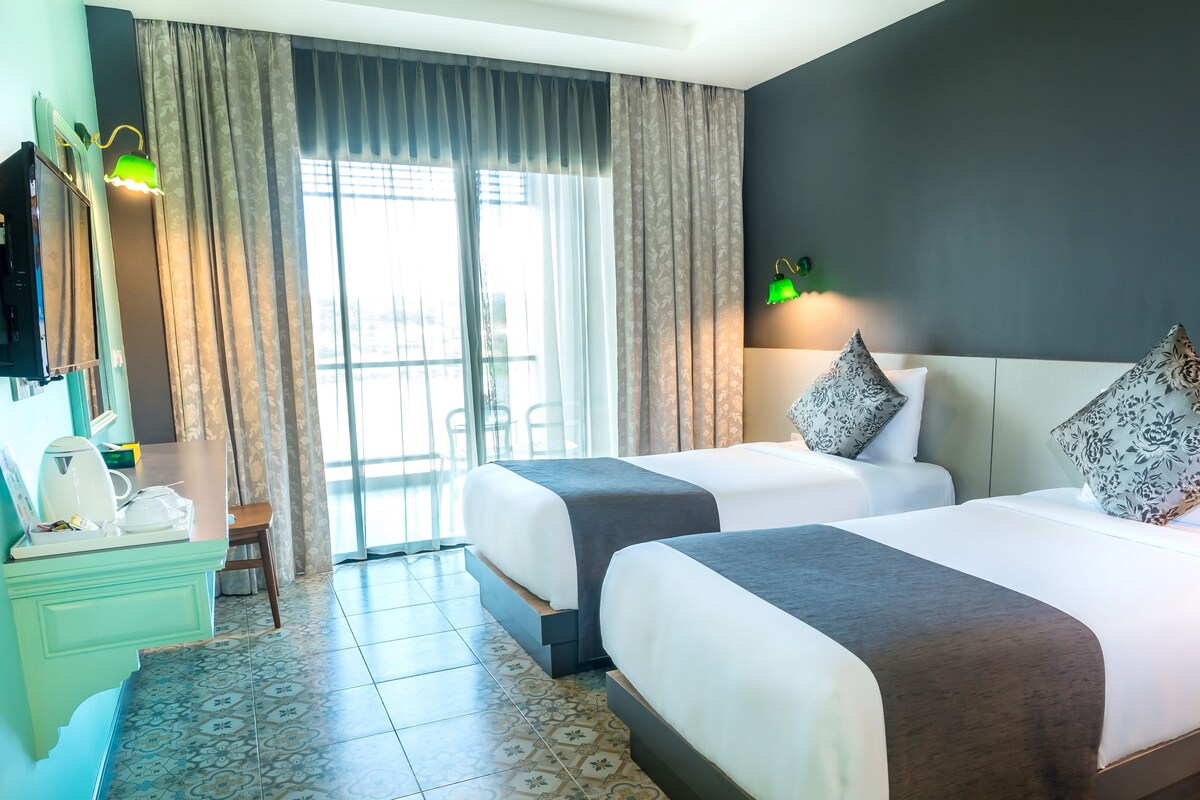 Ein Hotelzimmer mit zwei Betten, einem Schreibtisch mit Telefon und einem Sessel.