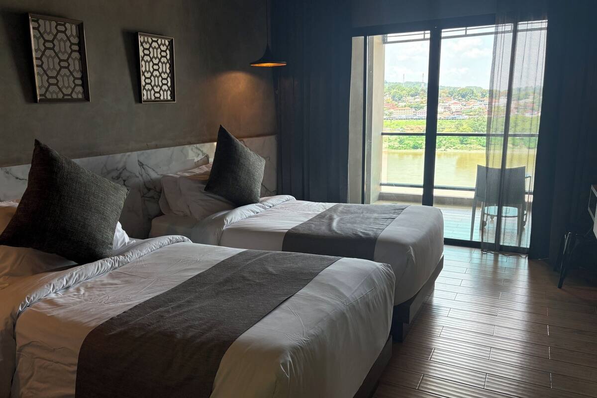 Habitación de hotel con dos camas, un ventanal con vistas y una lámpara en el techo.