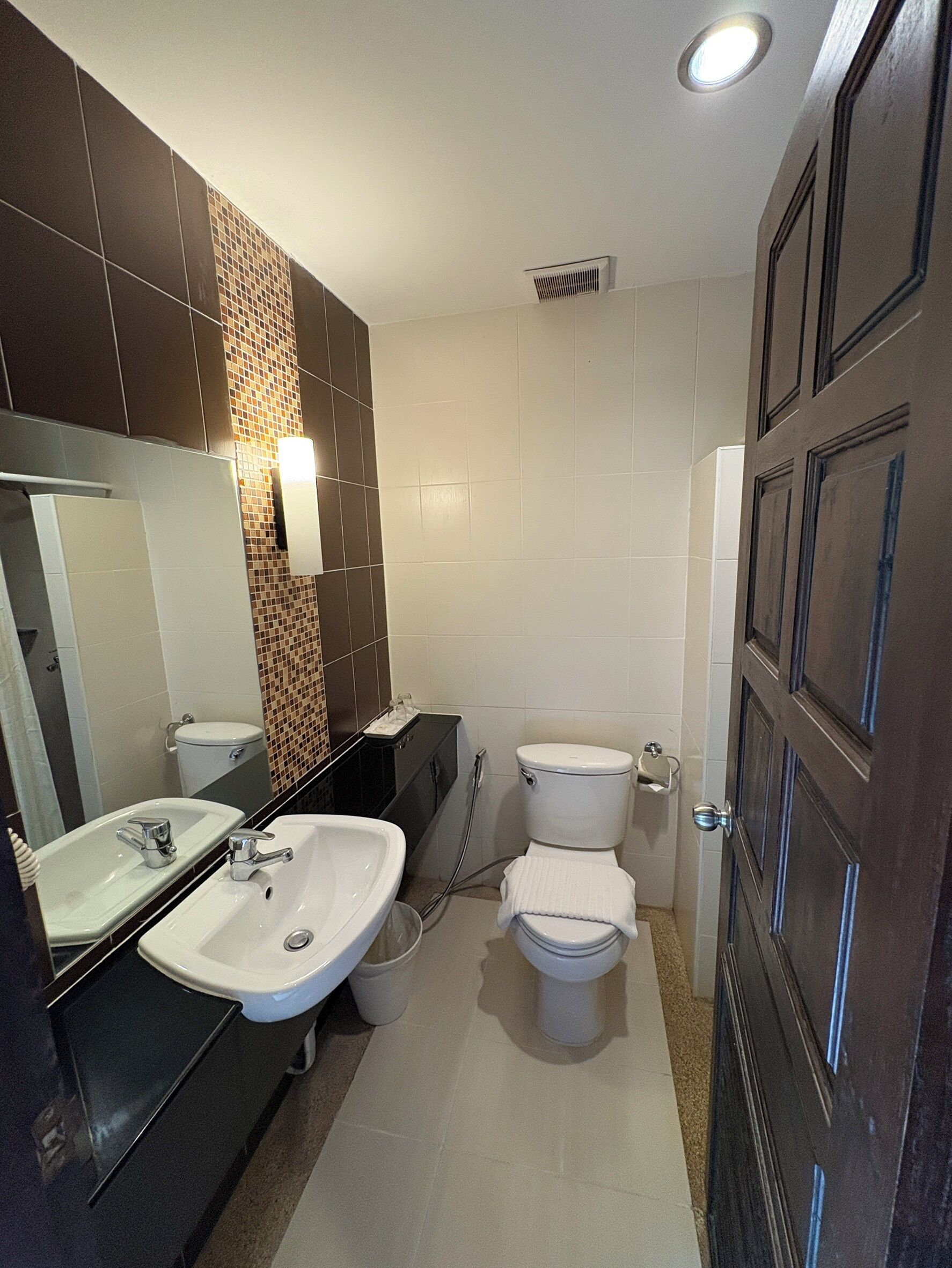 A bathroom with two toilets, a sink, a mirror, and a shower.