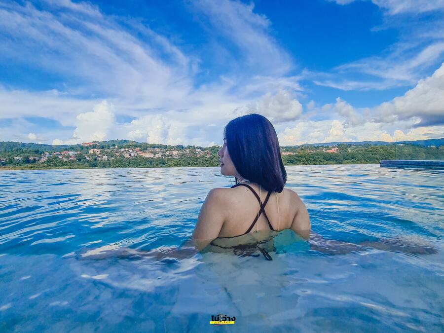 Uma pessoa em uma piscina com vista para uma cidade e montanhas ao longe.