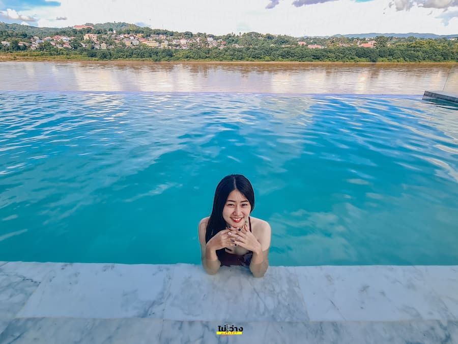 A person sitting at the edge of a pool with a view of a hillside town in the background.