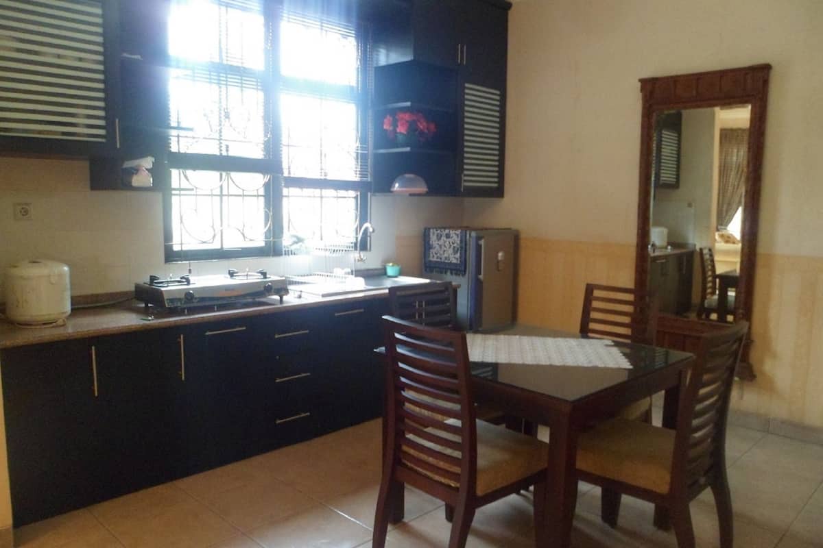 A compact kitchen with dark cabinetry, a dining table with chairs, and a small refrigerator.