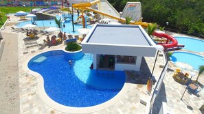 A swimming pool with a small building, a water slide, and lounge chairs. - Resort do Lago (Caldas Novas)