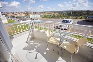 A balcony with two chairs and a table, overlooking a parking area and distant buildings. - Resort do Lago (Caldas Novas)