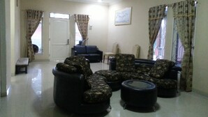 A living room with patterned sofas, a bench, and a dining table. - Kota Bunga C (Cipanas)