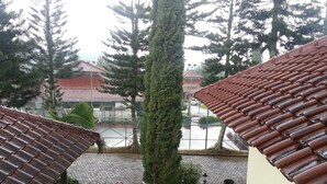 A courtyard with a tiled roof, a central tree, and a small seating area. - Kota Bunga C (Cipanas)