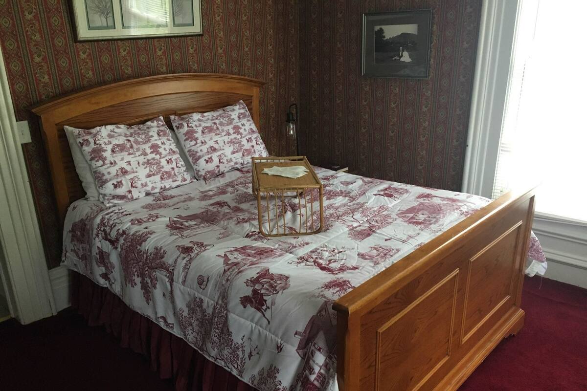 Une chambre à coucher avec un lit en bois, une literie à motifs floraux et un papier peint à dessins.