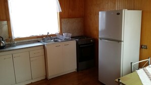 Una cocina compacta con pileta, estufa y refrigerador.