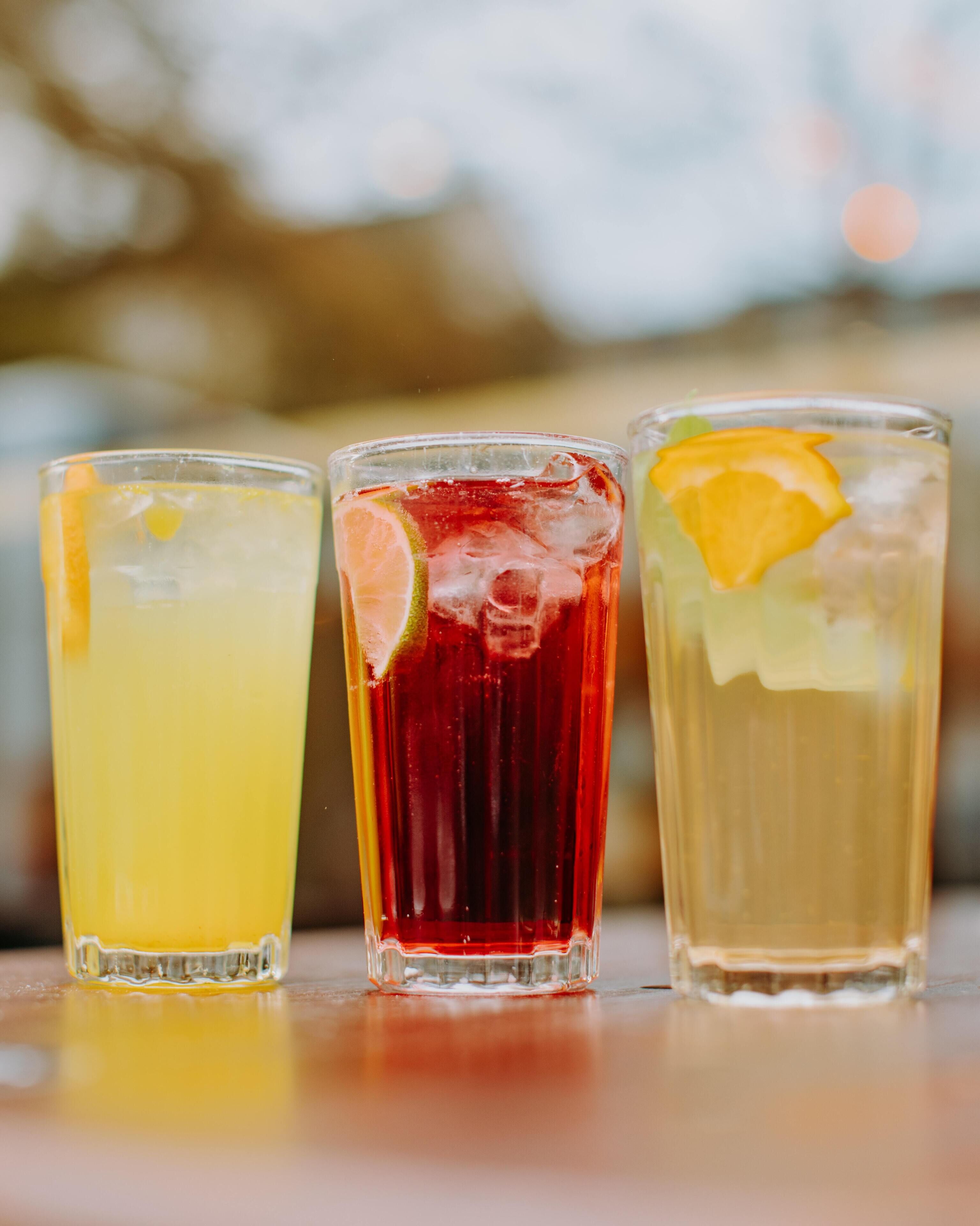 Three glasses of different colored beverages on a table.