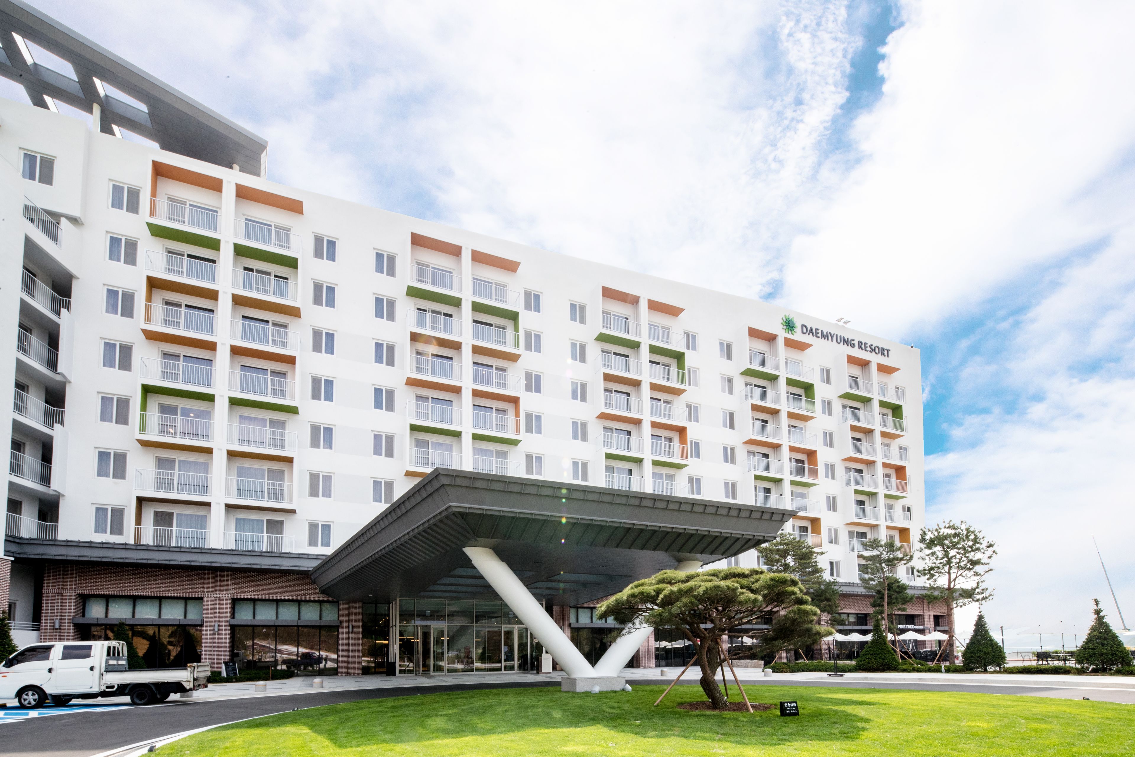Un hotel de varios pisos con diseño moderno, que cuenta con balcones y una entrada destacada con zona cubierta.
