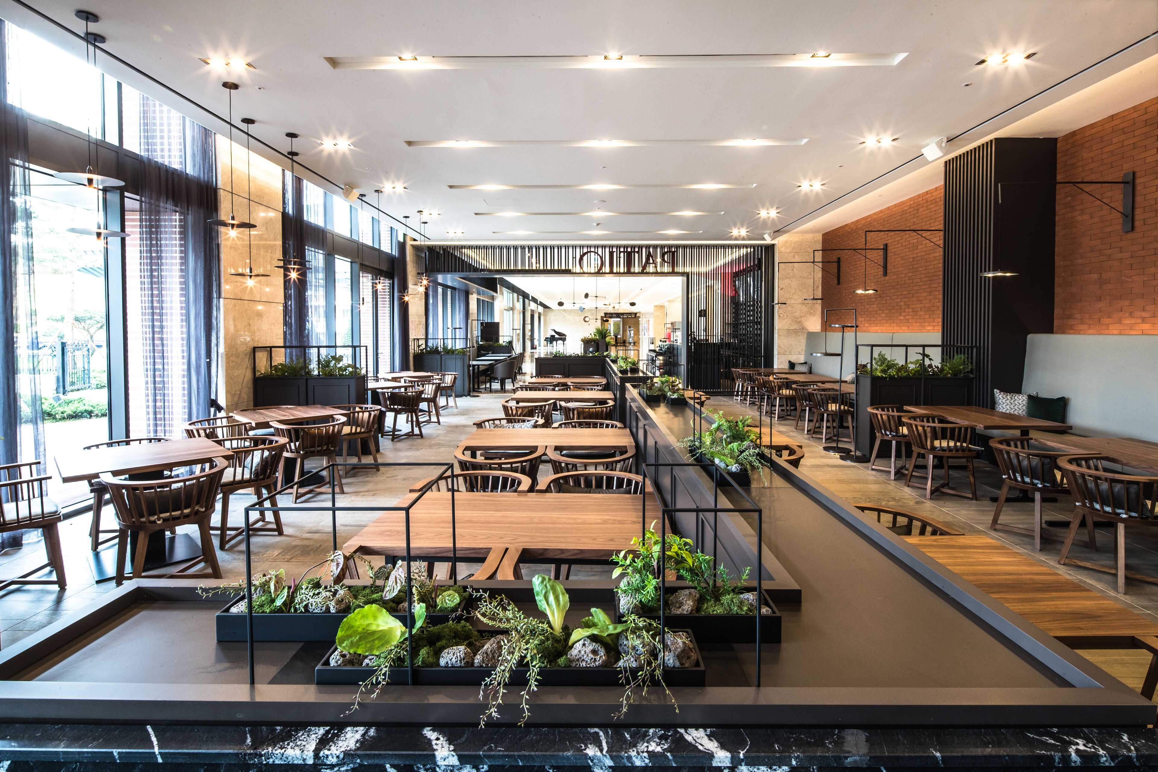 Un restaurant spacieux, doté de hauts plafonds, d’un éclairage moderne et offrant différents types d’aménagements pour s’asseoir.