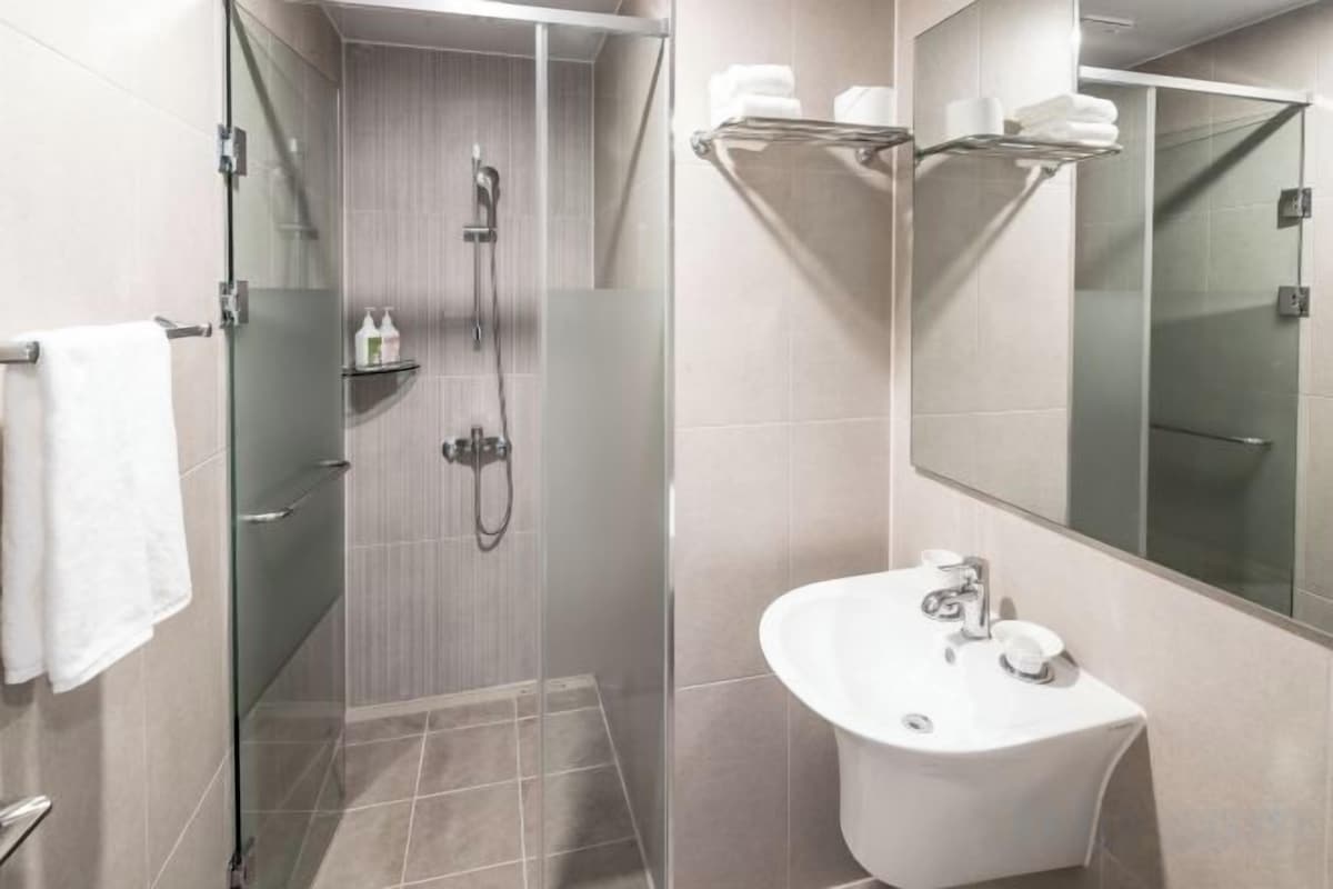 A modern bathroom with a glass-enclosed shower, a sink with a mirror, and a towel rack.