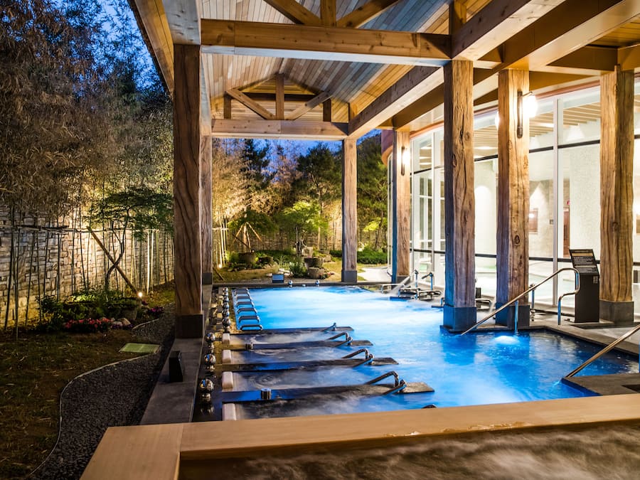 A heated outdoor pool with wooden beams and a stone wall.