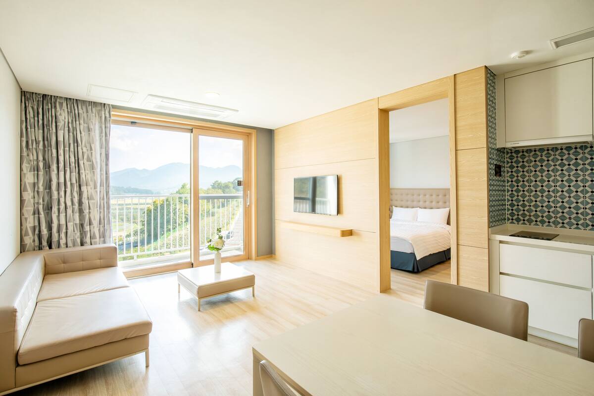Et moderne hotelværelse med balkon, sofa, spisebord og seng.