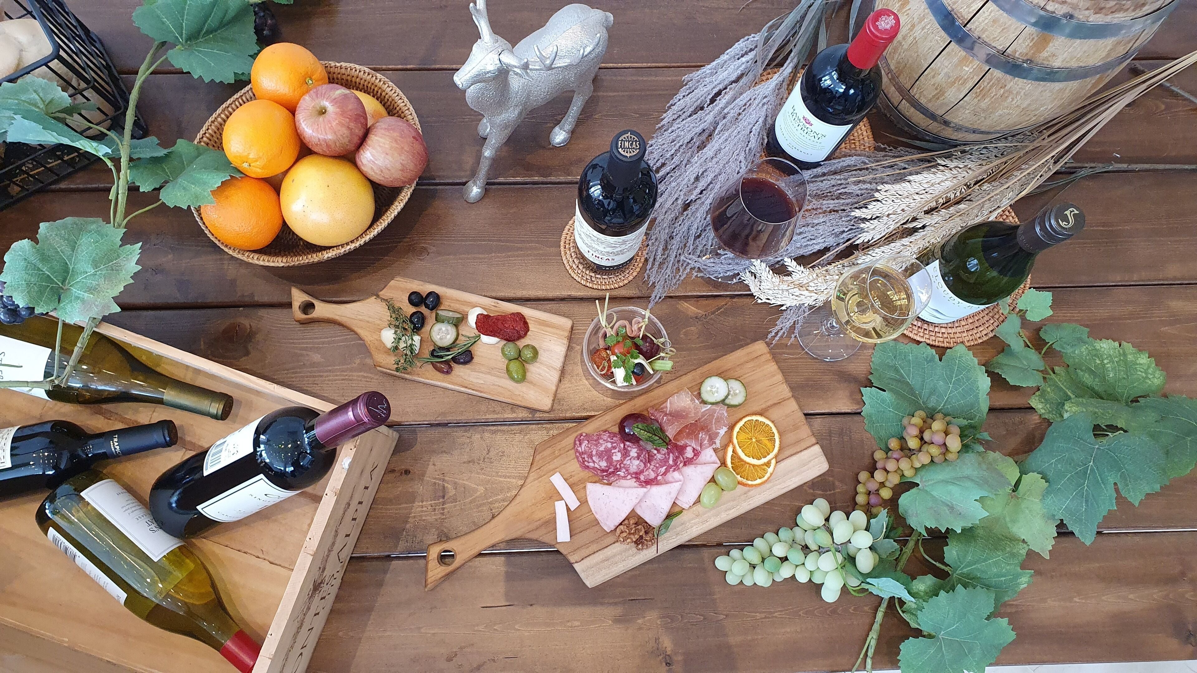 A wooden table with various food items, wine bottles, and a decorative silver fox figurine.