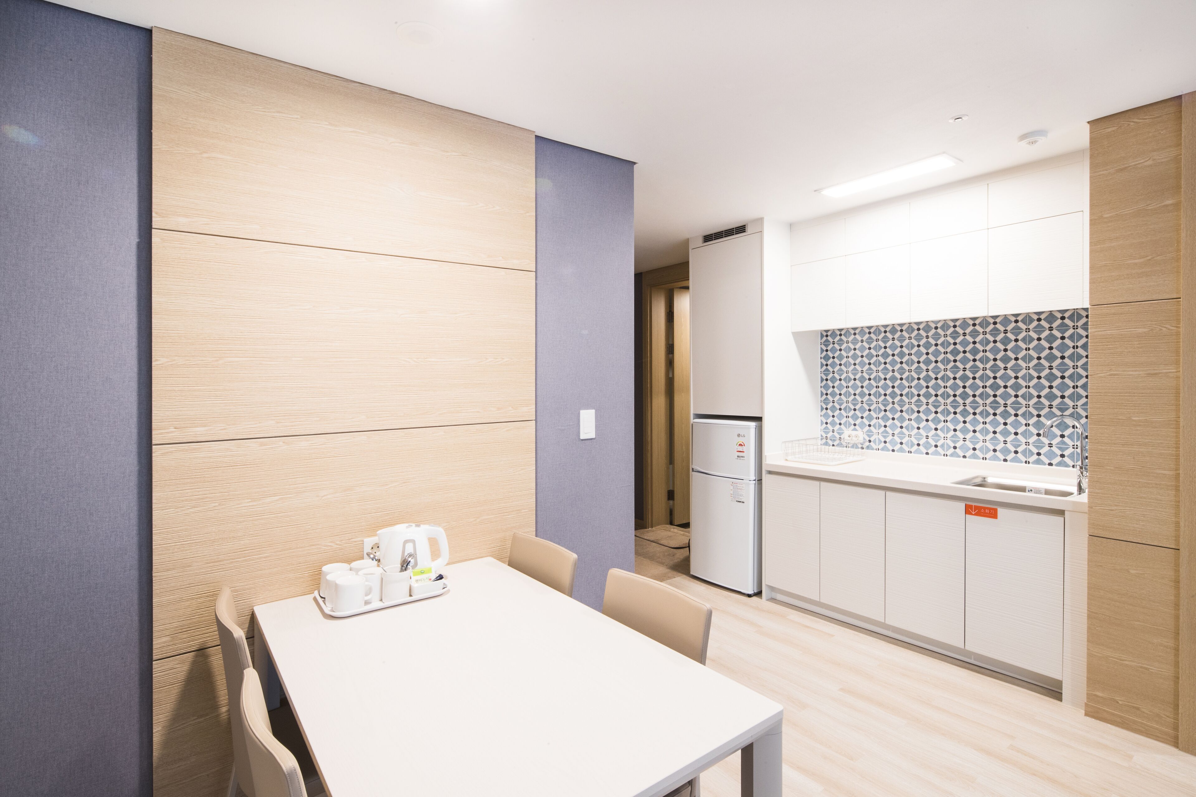 Una cocina moderna con encimera blanca, horno empotrado y refrigerador.