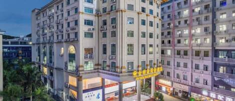 A multi-story hotel with a central courtyard, multiple balconies, and a ground-level retail area.